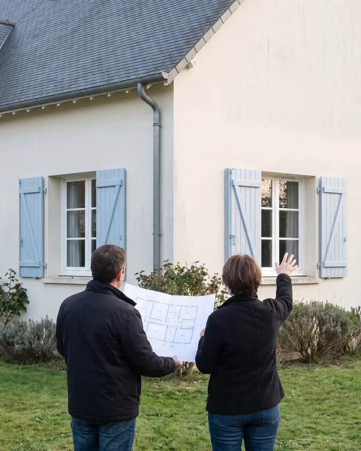 Illustration : deux personnes de dos étudient les plans d'une extension devant une maison