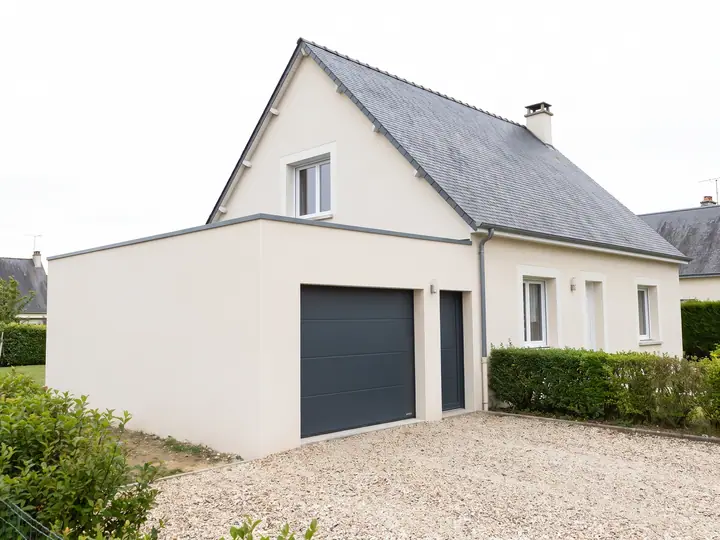 Illustration : extension de plain-pied créant un garage accolé à une maison au toit d'ardoise
